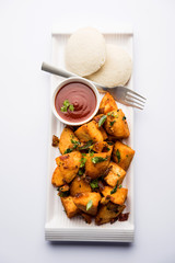 Masala fried Idlies or Idli fry - south indian Snack made using with leftover idly served with tomato ketchup. selective focus