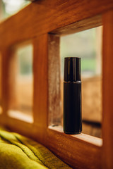 Essential oils roll on perfume in a dark brown glass bottle among nature background. Beauty...