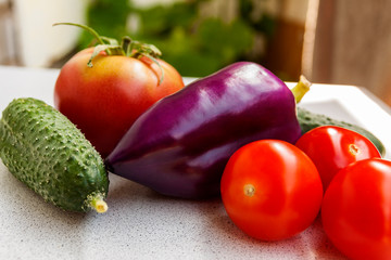 Pepper of unusual color surrounded by tomato and cucumber