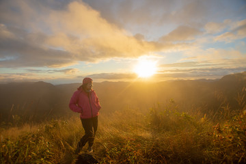 rear of happy woman stand on top mountain looking view with sunrise and mist at Doi Langka Luang, Chiang Rai province. soft focus.