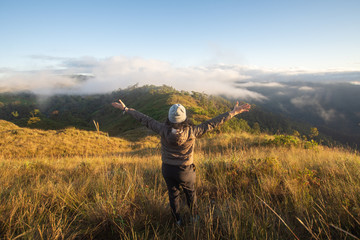 rear of happy woman stand on top mountain looking view with mist and cloud at Doi Langka Luang, Chiang Rai province. soft focus.