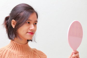 young woman using a hand mirror