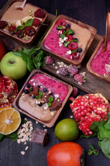 Smoothie bowl of two colours topped with chocolate pieces, bilberries, oatmeal flakes, mint and bran