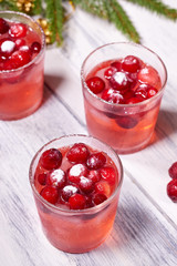 Glasses with cranberry juice on white wooden background with pine branch in the background. Christmas tree