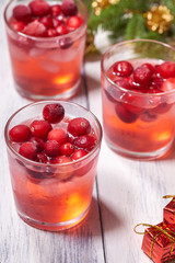 Glasses with cranberry juice on white wooden background with pine branch in the background. Christmas tree
