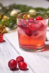Glasses with cranberry juice on white wooden background with pine branch in the background. Christmas tree