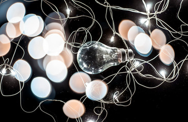 Close up of a bulb on wooden surface with colorful blurred background or bokeh of Christmas lights...