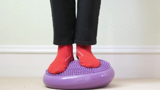 Balance board ankle exercise purple inflatable wobble feet close up red socks for rehabilitation of foot or knee joint injuries