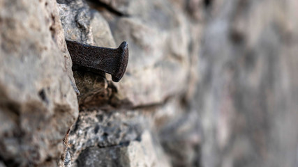 Close-up photo. Fragment of an old masonry wall with a forged iron nail.