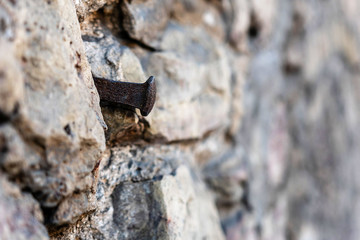 Close-up photo. Fragment of an old masonry wall with a forged iron nail.