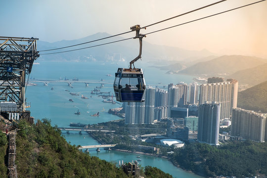 Ngong Ping Cable car with tourists over harbor, mountains and city background, to visit the Tian Tan or the Big Buddha located at Po Lin Monastery in Lantau Island. landmark and popular in Hong Kong