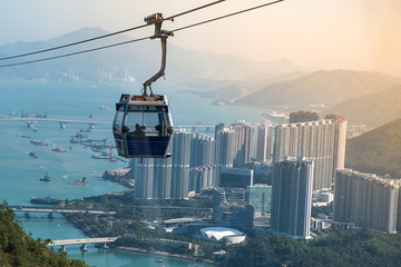 Ngong Ping Cable car with tourists over harbor, mountains and city background, to visit the Tian Tan or the Big Buddha located at Po Lin Monastery in Lantau Island. landmark and popular in Hong Kong