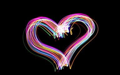 Pink and multi color light painting photography, gold, pink, green and blue heart shape, outline of heart in vibrant color against a black background