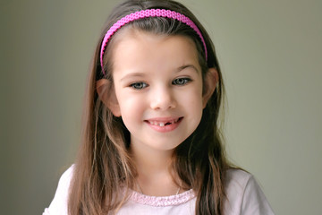 Caucasian white beautiful long haired brunette toothless girl with pink hair band. Smiling cute kid...