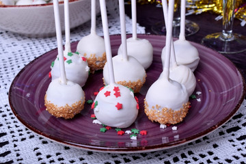 Cake pops covered in white chocolate and multicoloured sprinkles on a plate