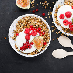 Breakfast homemade baked granola, red garden organic currants, figs and mint portions. Top view.