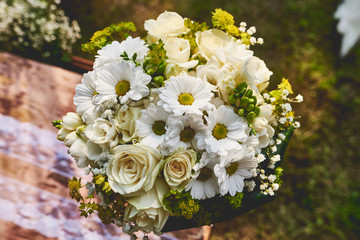 Obraz na płótnie Canvas Rustic wedding bouquet made of roses and daisies decorated with white lace and sackcloth