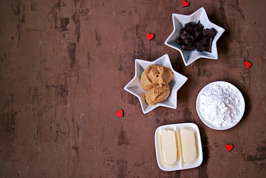 Ingredients for making homemade candies Buckeyes: peanut butter, bitter chocolate, powdered sugar, butter. Copy space, top view.