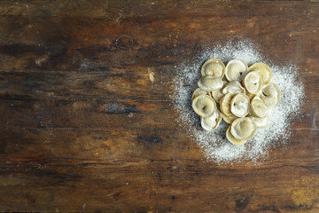 Italian ravioli, dumplings with meat on dark wooden old surface