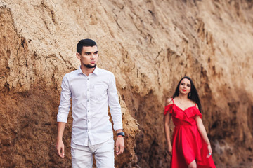 beautiful woman and bearded man posing on the background of a clay rock.