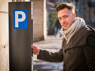 Close up of young man paying and waiting for a parking ticket to be dispensed from the ticket booth...