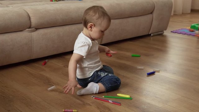 little girl is painting on the floor with crayons