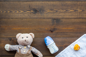 Handmade toys for newborn baby. Teddy bear. Feeding bottle with milk and dummy. Wooden background top view mockup