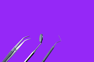 Dentist tools: mirror, dental probe and tweezers on purple background.