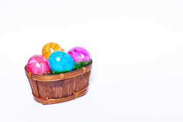 A basket filled with green grass and colorful easter eggs on white background with copy space