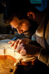 male craftsman violin maker working on a new violin