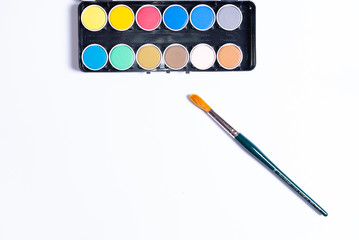 A colorful painting set and a paintbrush on white background with copy space