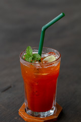 glass of ice tea with mint and lemon on wooden table