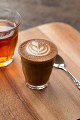 Piccolo Latte art in small glass on wooden desk