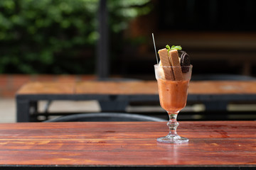 Vanilla sundae ice cream with wafer in a glass served on wooden desk in Asia canteen
