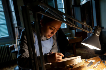 female craftsman violin maker working on a new violin