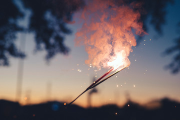A closeup of fireworks and sparklers during an evening sunset