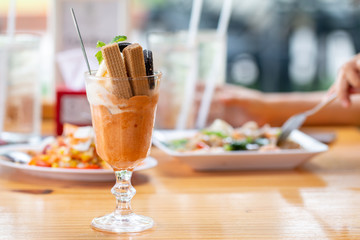 Vanilla sundae ice cream with wafer in a glass served on wooden desk in Asia canteen