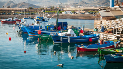 Panoramic view of moored colorful fishing vessels and boats at dockside on background of hilly shore