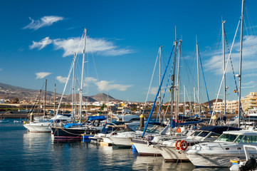 Fototapeta na wymiar Panoramic view of boats and yachts at dockside on background of hilly shore and cloudy blue sky