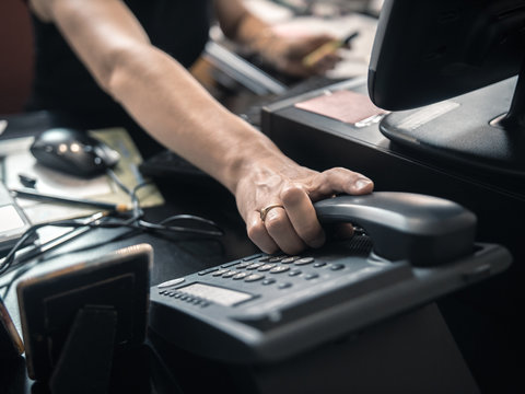 Main posée sur téléphone fixe de bureau