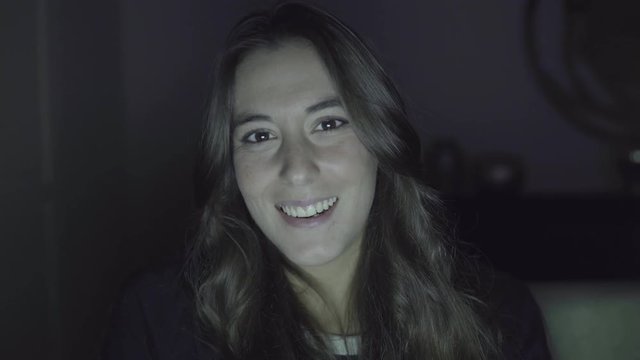 Beautiful happy girl talking during video chat. Cheerful young woman waving hand and smiling at camera during pleasant video conversation. Communication concept