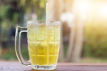 Iced Chrysanthemum tea on wooden desk side view with green natural out door background during day time in summer