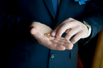 wedding rings on the palm of the groom