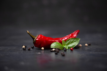 chili pepper with basil and peppercorns on a rustic surface