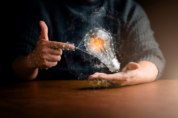 business man hand show bulb and drawing infographic icon in hand dark blackground