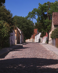 a narrow street of old towns with paving stones; empty street, along the edges of the old building...