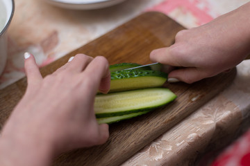Woman cuts cucumbers on the cutting board.