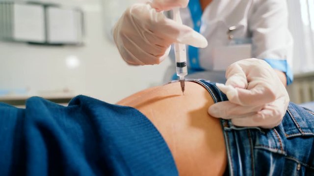 Woman doctor makes an intramuscular injection to the gluteus maximus muscle.