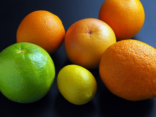 Green grapefruit, lemon and oranges on a dark background
