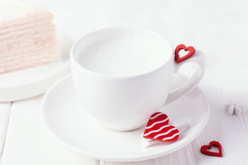 Coffee with milk foam and red hearts on a white background